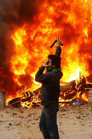 Un militant de l'opposition à Téhéran devant des motos de la police en feu. Un militant de l'opposition à Téhéran devant des motos de la police en feu.