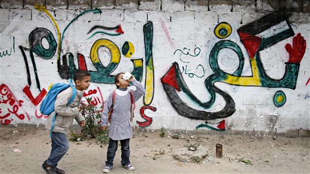 Des écoliers palestiniens à Gaza passent devant un graffiti en arabe invitant à la fin de la division. Des écoliers palestiniens à Gaza passent devant un graffiti en arabe invitant à la fin de la division.