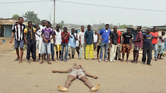 Des résidents observent le cadavre d'un homme tué par balle dans les rues d'Abidjan en janvier 2011. Des résidents observent le cadavre d'un homme tué par balle dans les rues d'Abidjan en janvier 2011.