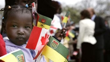 Une jeune réfugiée du Soudan brandissant des drapeaux du Canada et de la Saskatchewan à Régina, en 2006. Une jeune réfugiée du Soudan brandissant des drapeaux du Canada et de la Saskatchewan à Régina, en 2006.