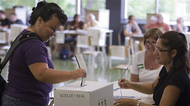 Une électrice dépose son bulletin de vote dans l'urne dans la circonscription de Vanier-Les Rivières. Une électrice dépose son bulletin de vote dans l'urne dans la circonscription de Vanier-Les Rivières.