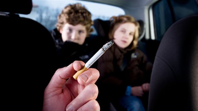 Une femme fume dans une voiture dont certains passagers sont des enfants. Une femme fume dans une voiture dont certains passagers sont des enfants.