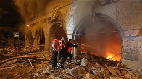 Les pompiers palestiniens tentent de maîtriser l'incendie qui a pris naissance après un raid israélien contre la Banque nationale islamique dans la ville de Gaza. Les pompiers palestiniens tentent de maîtriser l'incendie qui a pris naissance après un raid israélien contre la Banque nationale islamique dans la ville de Gaza.