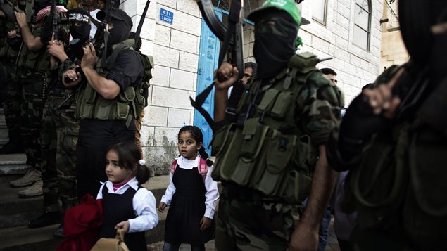 Des enfants palestiniennes dépassent des militants du Hamas armés réunis pour des funérailles à Gaza Des enfants palestiniennes dépassent des militants du Hamas armés réunis pour des funérailles à Gaza