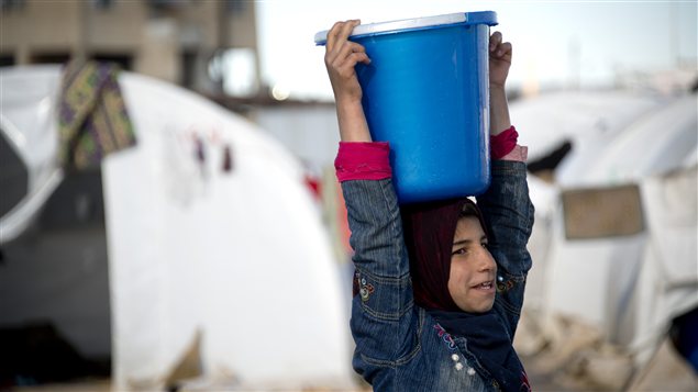 Une enfant transporte de l’eau dans un camp de réfugiés Une enfant transporte de l’eau dans un camp de réfugiés