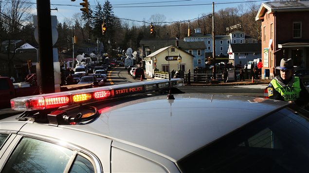 Des policiers montent la garde devant l'entrée de la rue qui mène à l'école Sandy Hook. Des policiers montent la garde devant l'entrée de la rue qui mène à l'école Sandy Hook.