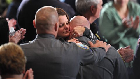 Une femme réconforte un membre du corps de police de Newtown quelques minutes avant que Barack Obama ne prononce son discours lors de la cérémonie religieuse. Une femme réconforte un membre du corps de police de Newtown quelques minutes avant que Barack Obama ne prononce son discours lors de la cérémonie religieuse.