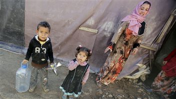 Des réfugiés syriens attendent à côté de leurs abris de fortune dans un champ de Saadnayel, dans la vallée de la Bekaa, au Liban, le 12 décembre 2012. Des réfugiés syriens attendent à côté de leurs abris de fortune dans un champ de Saadnayel, dans la vallée de la Bekaa, au Liban, le 12 décembre 2012.