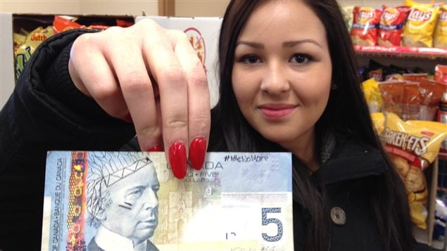 Ali Fontaine tient un billet de cinq dollars modifié Ali Fontaine tient un billet de cinq dollars modifié