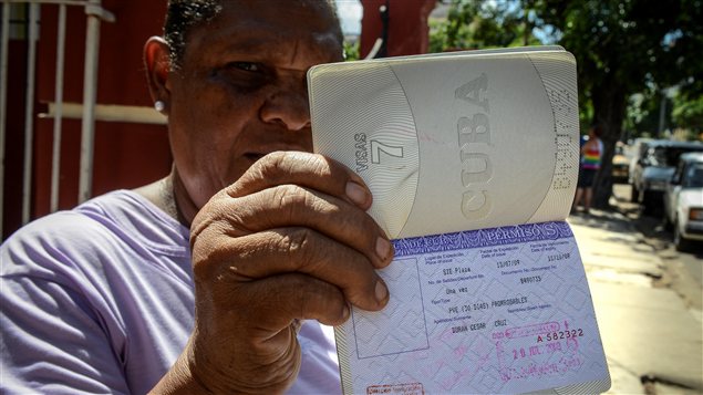 Une Cubaine montre sa carte blanche, un permis de sortie du pays dont les citoyens n'ont désormais plus besoin pour sortir du pays Une Cubaine montre sa carte blanche, un permis de sortie du pays dont les citoyens n'ont désormais plus besoin pour sortir du pays