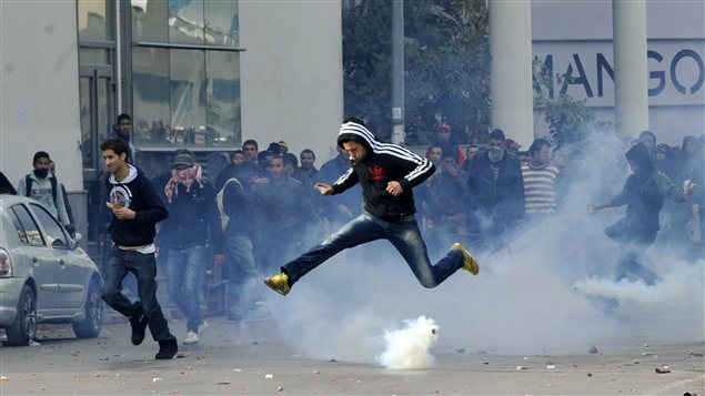Un manifestant saute par dessus une bonbonne de gaz lacrymogènes lors d'une manifestation devant les bureaux du ministère de l'Intérieur à Tunis. Un manifestant saute par dessus une bonbonne de gaz lacrymogènes lors d'une manifestation devant les bureaux du ministère de l'Intérieur à Tunis.