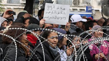 Des manifestantes chantent derrière un barbelé devant le ministère de l'Intérieur, à Tunis. Des manifestantes chantent derrière un barbelé devant le ministère de l'Intérieur, à Tunis.