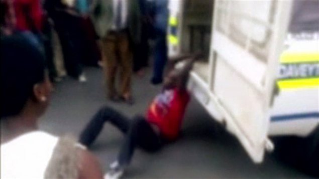 Une image extraite de la vidéo montre l'homme attaché au camion de police. Une image extraite de la vidéo montre l'homme attaché au camion de police.