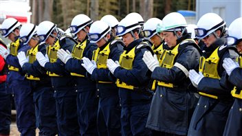 Des policiers japonais respectent une minute de silence alors qu'ils recherchent toujours des victimes du tsunami du 11 mars 2011, à Ishinomaki Des policiers japonais respectent une minute de silence alors qu'ils recherchent toujours des victimes du tsunami du 11 mars 2011, à Ishinomaki