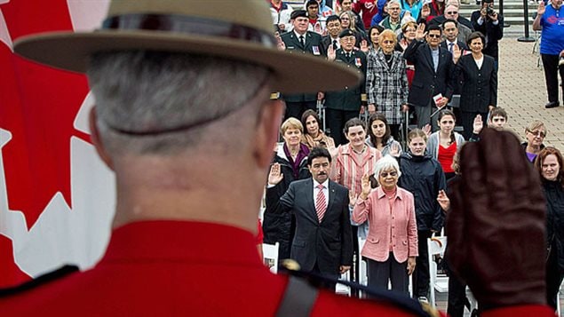 Un agent de la GRC lève la main devant un groupe de 60 immigrants venus prêter serment lors d'une cérémonie spéciale tenue l'an dernier à Vancouver pour le Jour du Canada. Un agent de la GRC lève la main devant un groupe de 60 immigrants venus prêter serment lors d'une cérémonie spéciale tenue l'an dernier à Vancouver pour le Jour du Canada.