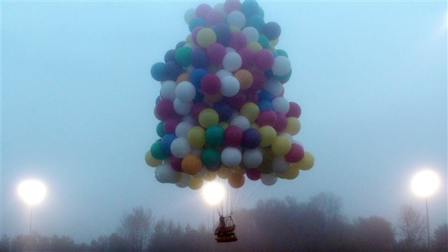 Un homme s'envole dans les airs à l'aide de ballons gonflés à l'hélium Un homme s'envole dans les airs à l'aide de ballons gonflés à l'hélium