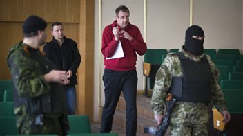 Des hommes cagoulés ont escorté les membres de l'OSCE qui ont pris part à une conférence de presse à Slaviansk, le 27 avril Des hommes cagoulés ont escorté les membres de l'OSCE qui ont pris part à une conférence de presse à Slaviansk, le 27 avril