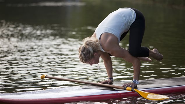 Une femme exerce une position de yoga sur une planche de surf.