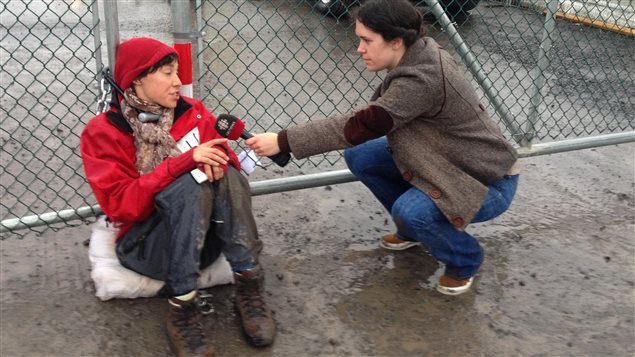 Une des manifestantes attachées à une des portes menant à la raffinerie de Suncor à Montréal-Est Une des manifestantes attachées à une des portes menant à la raffinerie de Suncor à Montréal-Est