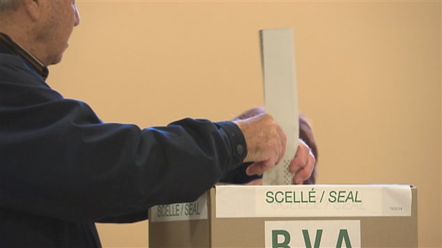 Un électeur dépose son bulletin de vote dans une urne. Un électeur dépose son bulletin de vote dans une urne.