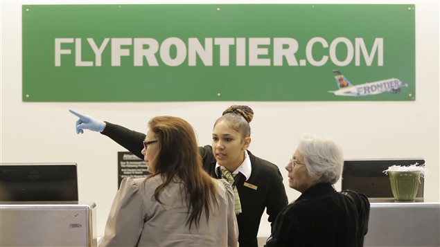 Une employée de Frontier Airlines à l'aéroport de Cleveland dirige des clients. Une employée de Frontier Airlines à l'aéroport de Cleveland dirige des clients.