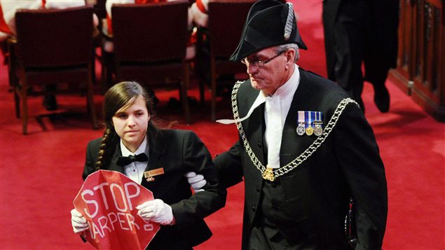 Le sergent d'armes Kevin Vickers escorte la jeune page Brigette DePape hors du Sénat, alors que le gouverneur général David Johnston livre le discours du Trône. Le sergent d'armes Kevin Vickers escorte la jeune page Brigette DePape hors du Sénat, alors que le gouverneur général David Johnston livre le discours du Trône.