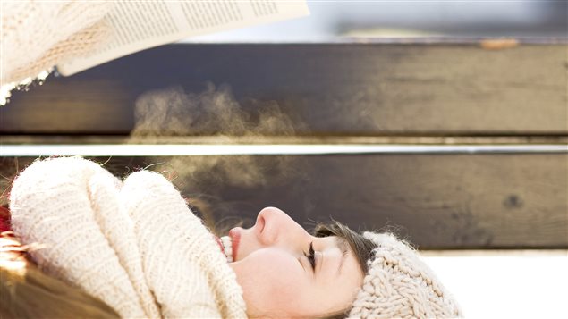 Femme lisant sur un banc en hiver Femme lisant sur un banc en hiver