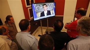 Des Grecs regardent l'allocution télévisée du premier ministre Alexis Tsipras après la victoire du non. Des Grecs regardent l'allocution télévisée du premier ministre Alexis Tsipras après la victoire du non.