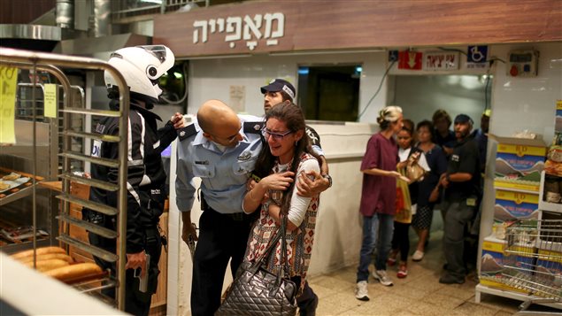 Un soldat israélien console une jeune femme à la sortie d'un supermarché où est survenue une attaque au couteau Un soldat israélien console une jeune femme à la sortie d'un supermarché où est survenue une attaque au couteau