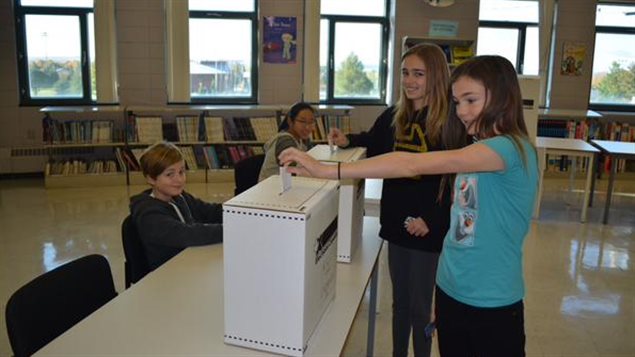 Des élèves de l’école secondaire des pionniers à Saint-Augustin-des-Desmaures, au Québec, déposent leur bulletin de vote. Des élèves de l’école secondaire des pionniers à Saint-Augustin-des-Desmaures, au Québec, déposent leur bulletin de vote.