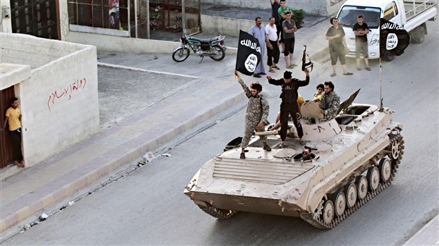 Des djihadistes brandissent le drapeau du groupe armé État islamique. Des djihadistes brandissent le drapeau du groupe armé État islamique.