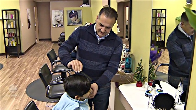 Mohammad Kurdi coiffe un jeune garçon dans son nouveau salon de coiffure. Mohammad Kurdi coiffe un jeune garçon dans son nouveau salon de coiffure.