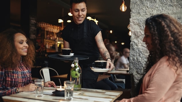 Un serveur sert deux clientes dans un restaurant. Un serveur sert deux clientes dans un restaurant.