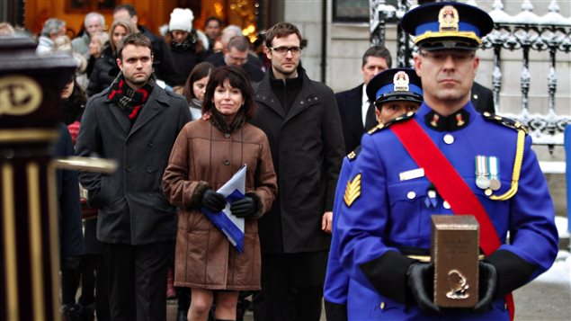 La femme de Jean-Paul L'Allier, Johanne Mongeau, marche derrière l'urne qui contient les cendres de son mari à la fin des funérailles La femme de Jean-Paul L'Allier, Johanne Mongeau, marche derrière l'urne qui contient les cendres de son mari à la fin des funérailles
