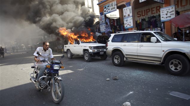 Une voiture brûle durant une manifestation à Port-au-Prince, à Haïti, le 18 janvier 2016. Une voiture brûle durant une manifestation à Port-au-Prince, à Haïti, le 18 janvier 2016.