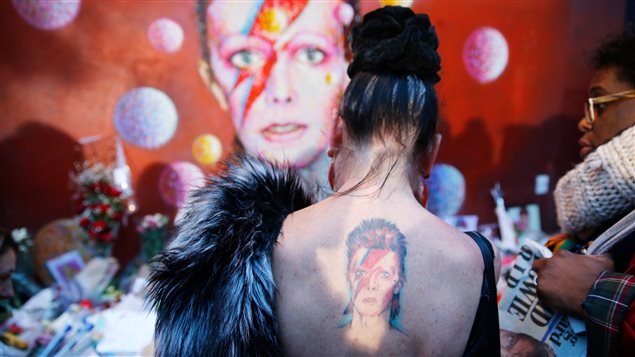 À Londres, une femme arbore un tatouage de Ziggy Stardust devant une murale représentant le personnage qu'incarnait David Bowie, où a grandi la légende du rock.