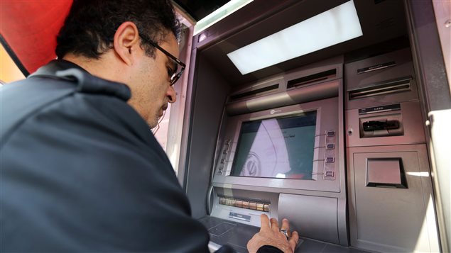 Un Iranien retire de l'argent à un guichet bancaire de Téhéran. Un Iranien retire de l'argent à un guichet bancaire de Téhéran.