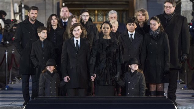 À l'avant-plan, devant le cercueil de René Angélil, Céline Dion et ses fils René-Charles, Eddy et Nelson, et derrière, d'autres membres de la famille Angélil-Dion. À l'avant-plan, devant le cercueil de René Angélil, Céline Dion et ses fils René-Charles, Eddy et Nelson, et derrière, d'autres membres de la famille Angélil-Dion.