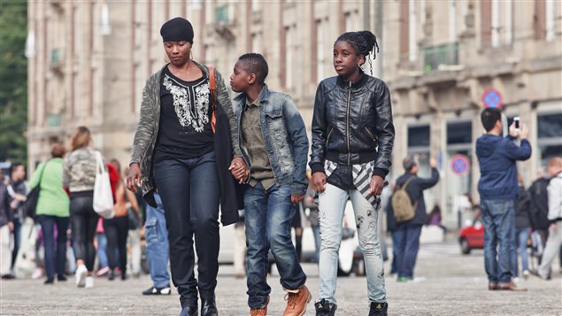 Une famille de touristes déambule tranquillement sur la Place du Dam à Amsterdam.