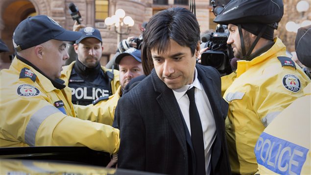 Jian Ghomeshi quitte le tribunal escorté par des policiers. Jian Ghomeshi quitte le tribunal escorté par des policiers.