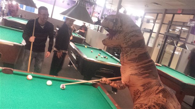 Conrad le tyrannosaure essaie d’améliorer ses talents de joueur au billard, à Winnipeg. Conrad le tyrannosaure essaie d’améliorer ses talents de joueur au billard, à Winnipeg.
