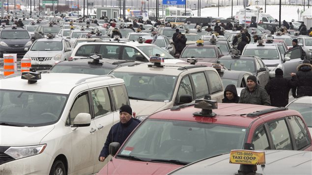 Plusieurs centaines de chauffeurs de taxi bloquent la circulation à l'aéroport Trudeau de Montréal. le 10 février, pour protester contre Uber. Plusieurs centaines de chauffeurs de taxi bloquent la circulation à l'aéroport Trudeau de Montréal. le 10 février, pour protester contre Uber.