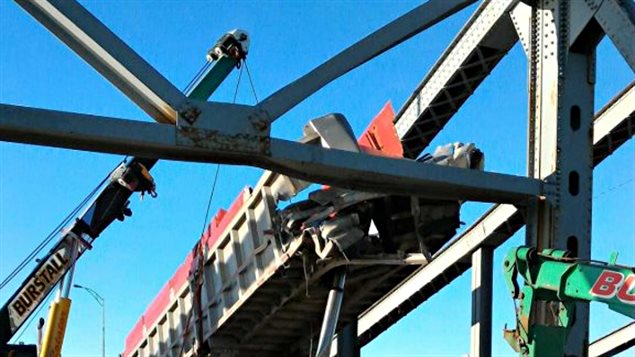 Une équipe s'affaire à retirer une benne d'un camion coincée dans la structure du pont Mercier. Une équipe s'affaire à retirer une benne d'un camion coincée dans la structure du pont Mercier.