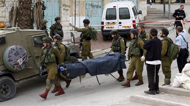 Des soldats israéliens transportent le corps d'un Palestinien abattu, à Hébron en Cisjordanie. Des soldats israéliens transportent le corps d'un Palestinien abattu, à Hébron en Cisjordanie.