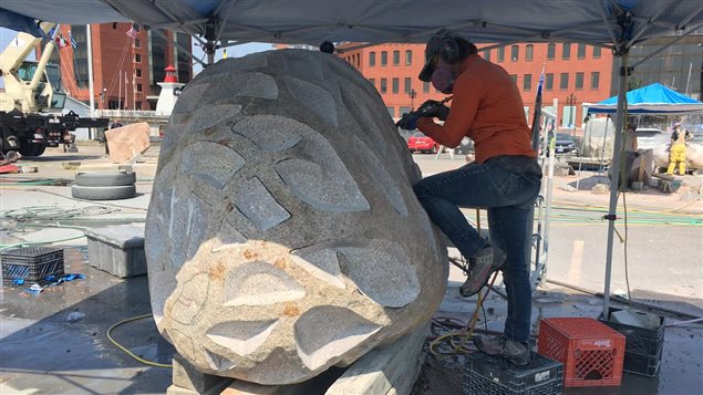 Une artiste sculpte un bloc de granite