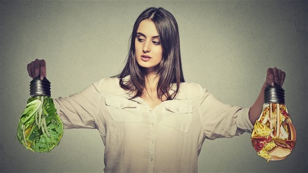 Une femme hésite entre des légumes et de la viande.