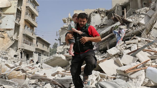 Un homme transporte un enfant en enjambant les ruines d'un bâtiment détruit à Alep, en Syrie. Un homme transporte un enfant en enjambant les ruines d'un bâtiment détruit à Alep, en Syrie.