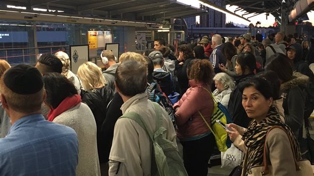 Des usagers du SkyTrain attendent sur le quai Des usagers du SkyTrain attendent sur le quai