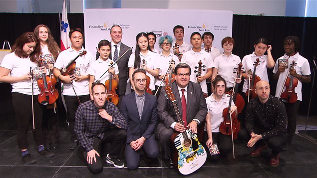 Robert Dumas, de Sun Life Québec, le maire de Montréal et trois membres du groupe Simple Plan entourés de jeunes musiciens
