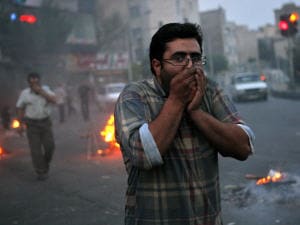 Un manifestant tente de se protéger des gaz lacrymogènes, à Téhéran. Un manifestant tente de se protéger des gaz lacrymogènes, à Téhéran.